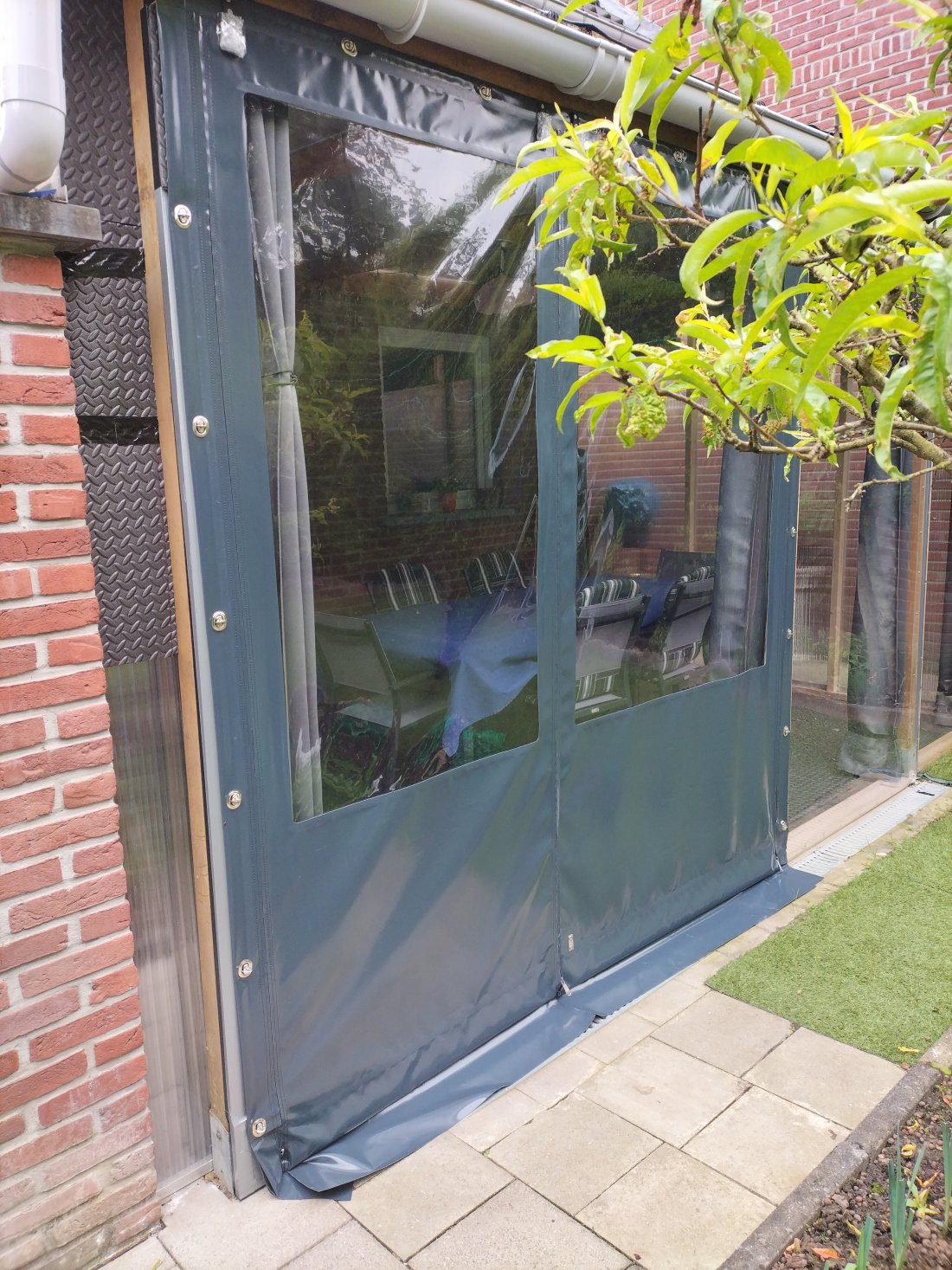 Verandadoek bevestigd met zeilogen en spanbanden aan een houten overkapping
