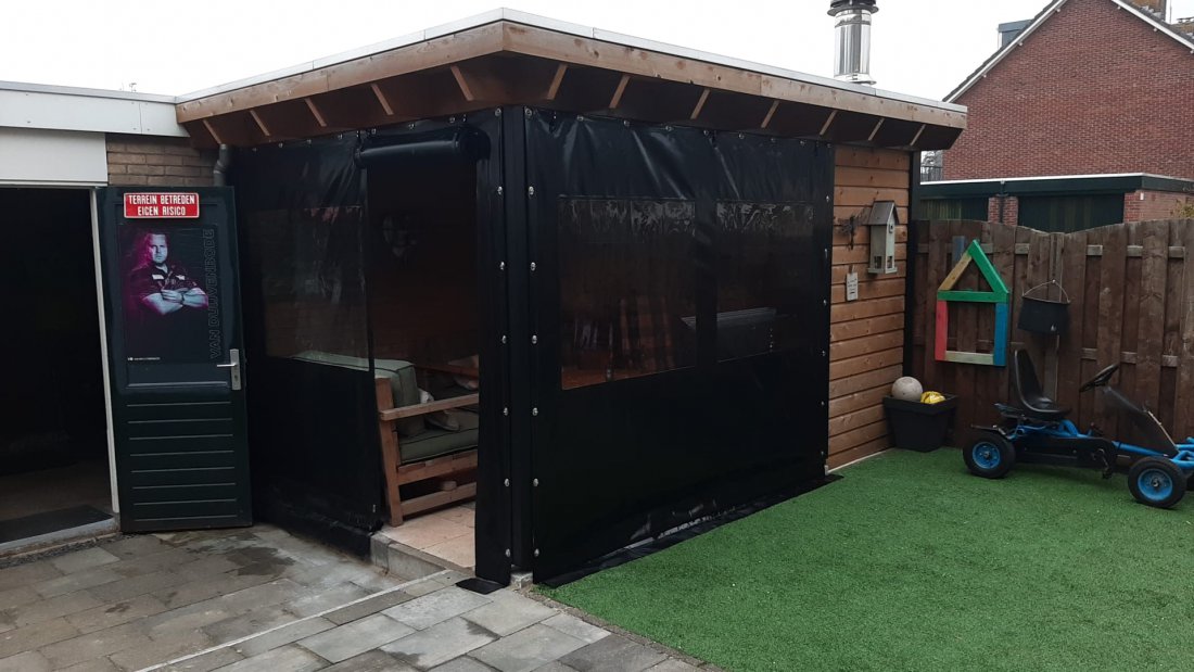 Donker verandadoek dat met haken aan een stalen frame is vastgezet