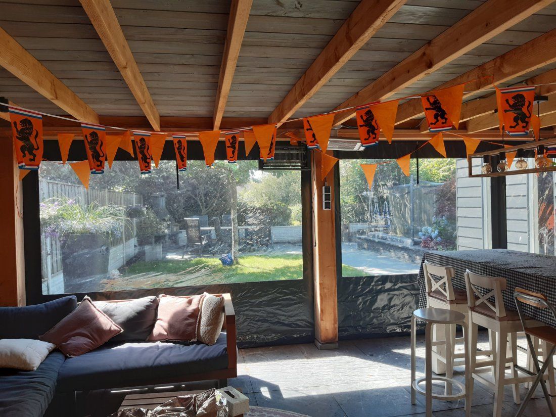Zicht vanuit een overdekte veranda door een verandazeil met ramen
